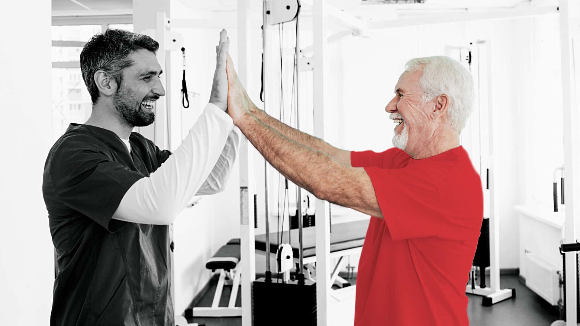 physical therapist offering a high five to a patient wearing a red shirt in a gym